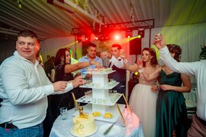 Colorful lighting effects create atmosphere during wedding cake celebration with guests.