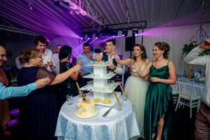 Purple mood lighting bathes wedding reception scene as guests gather around the cake table.