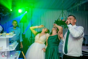 Party venue illuminated by green lighting with guests celebrating.