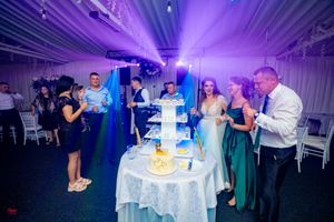 Reception hall with dramatic purple lighting and white table settings.