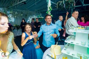 Event space decorated with greenery and white tables under atmospheric lighting.