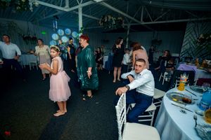 Wedding reception dance floor with guests dancing under atmospheric lighting.