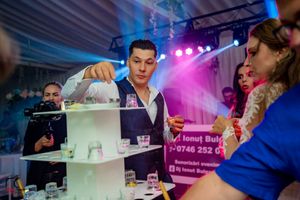 Wedding party enjoying drinks and entertainment with pink and blue mood lighting.