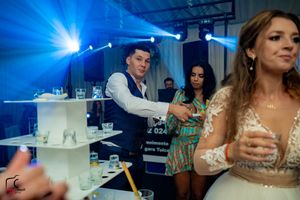 Wedding celebration with colorful lighting and guests enjoying drinks at a reception.