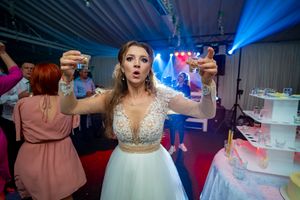 Reception party scene with bride holding treats amid blue lighting and dessert displays.