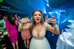 Wedding celebration with bride holding desserts under dramatic blue lighting effects.