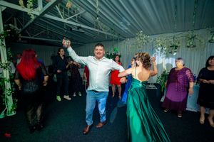 Wedding celebration with dancers in emerald green and white attire under ambient lighting.