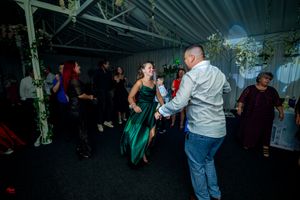 Guests dancing in a decorated indoor venue with green foliage accents.
