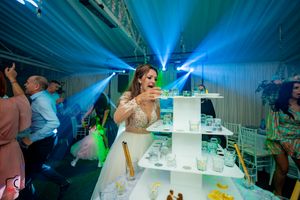 Wedding reception venue with blue lighting and a drink station setup in a decorated tent.