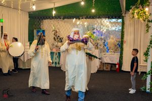 Wedding celebration in a decorated indoor venue with string lights and hanging floral arrangements.