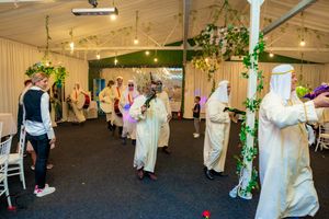 Wedding reception dance floor with string lights and greenery decorations in an elegant tent setting.