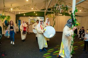 Musicians in traditional Middle Eastern dress perform with drums during an indoor celebration.