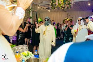 Performer in traditional Middle Eastern attire dances with gold accessories under decorative lighting.