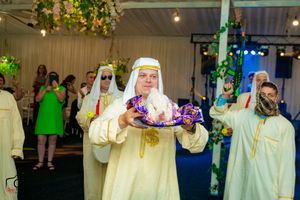 Musicians in traditional white robes perform with drums and instruments at an indoor venue.