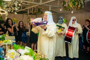 Traditional entertainment group performs with drums and treats at an indoor wedding reception.