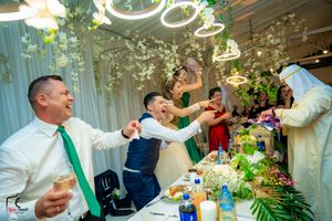 Guests toasting during a lively wedding celebration with traditional Middle Eastern entertainment.
