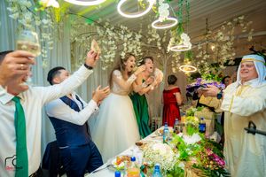 Celebratory toast at an elegant wedding reception with floral decor and decorative lighting.