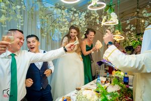 Festive wedding celebration scene with decorative lighting and floral arrangements in an indoor venue.