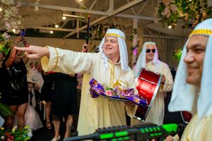 Wedding party celebration with guests enjoying entertainment under elegant ceiling decorations.