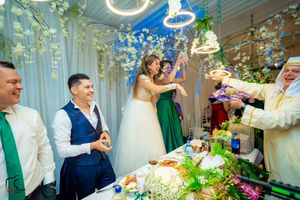Wedding celebration with guests enjoying festivities under elegant hanging lights and floral decor.