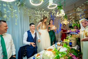 Joyful wedding reception scene with guests celebrating under decorative lighting and floral arrangements.