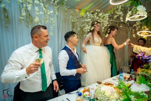 Wedding party celebrating at a beautifully decorated reception with hanging lights and greenery.