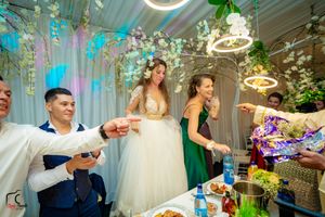 Wedding celebration scene with festive decorations, circular lighting fixtures, and floral arrangements in an elegant indoor venue.
