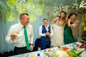 Wedding celebration with guests enjoying themselves under decorative lighting and floral arrangements.
