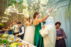 Wedding celebration with guests enjoying the festivities under hanging lights and floral decorations.