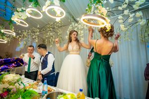 Elegant wedding reception with white draping, hanging lights and greenery decorations.