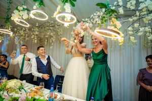Wedding celebration with guests dancing under decorative circular lighting and floral arrangements at reception.