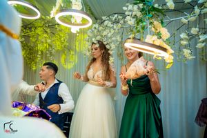 Wedding party dancing and celebrating under decorative greenery and ambient lighting.