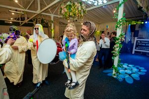 Lively wedding reception with guests dancing under floral arrangements and mood lighting.