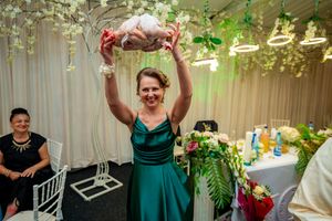 Wedding celebration with guests dancing under floral decorations and green accent lighting.