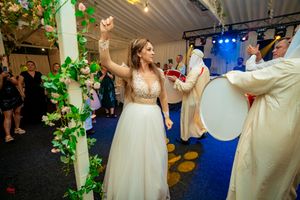 Wedding celebration in a decorated indoor venue with white and green decor and hanging lights.