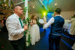 Wedding reception dance floor with atmospheric lighting and decorative greenery along support columns.