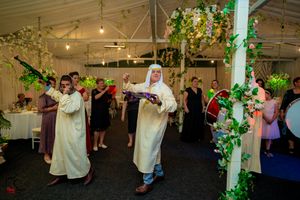 Reception venue features elegant floral arrangements and green vines wrapped around white pillars.