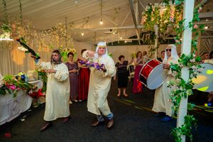 Wedding guests dance and mingle in a beautifully decorated reception hall with vine-covered pillars.