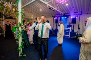 Wedding celebration in a decorated indoor venue with colorful mood lighting and floral arrangements.