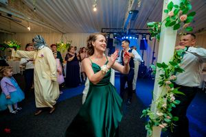 Wedding reception dance floor filled with guests enjoying festivities under blue and purple lighting.