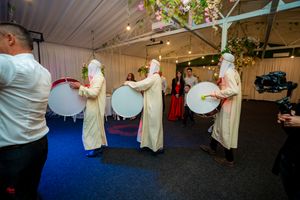 Wedding party dances in formation on a dark dance floor under decorative ceiling lights.