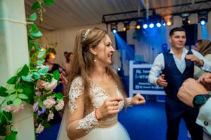 Reception venue features elegant green vine decorations and blue ambient lighting during evening celebrations.