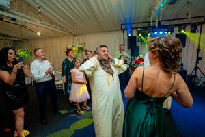 Wedding guests dancing and celebrating in formal attire under venue lighting.