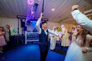 Joyous dancing celebration at wedding reception with purple and blue lighting effects.