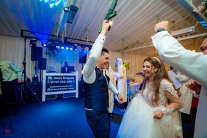 Celebratory dance moment at wedding reception with blue lighting and entertainment setup.