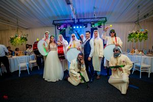 Wedding party members pose together under blue lighting in decorated reception tent.