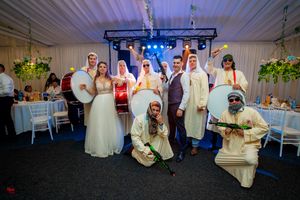Group photo at wedding reception showing guests in traditional Middle Eastern attire and formal wear.
