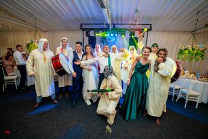 Wedding party poses together in a reception tent with colorful lighting and decorative elements.