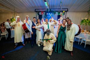 Group photo of wedding guests in mix of cultural dress and formal attire at reception.