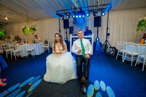Reception scene with formal attire and blue lighting against white draped walls.